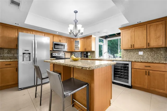 a kitchen with stainless steel appliances granite countertop a refrigerator a sink dishwasher a stove and a dining table with wooden floor