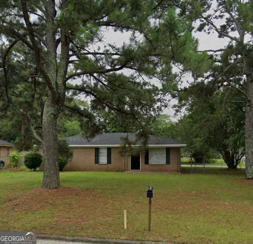 a front view of a house with a garden and trees