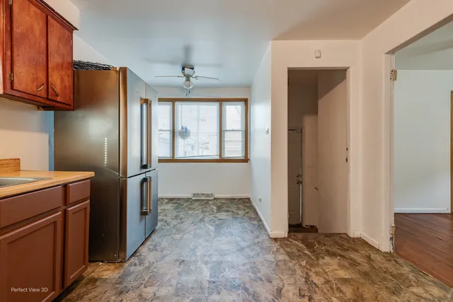 a view of a refrigerator in kitchen and an empty room with wooden floor