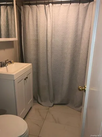 a bathroom with a sink a toilet a mirror and shower curtain