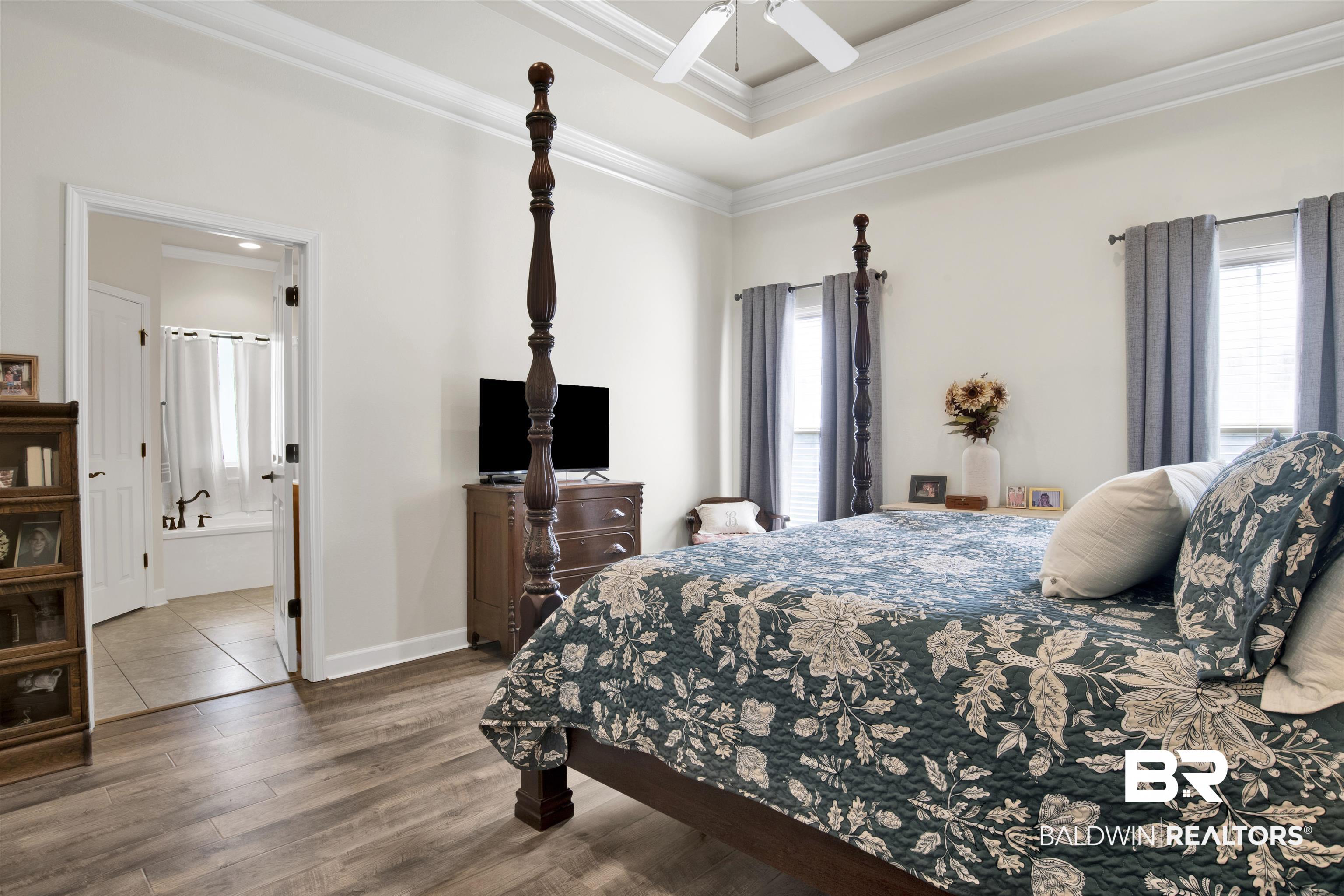 10368 Gayfer Rd Extension Fairhope, AL 36532 - Photo 20 of 43 Room featuring wood-finish flooring, a tray ceiling with crown molding, and a ceiling fan