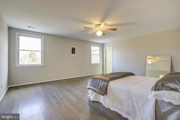 a spacious bedroom with a bed and wooden floor