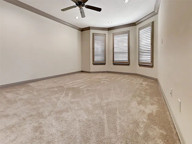 an empty room with windows and ceiling fan