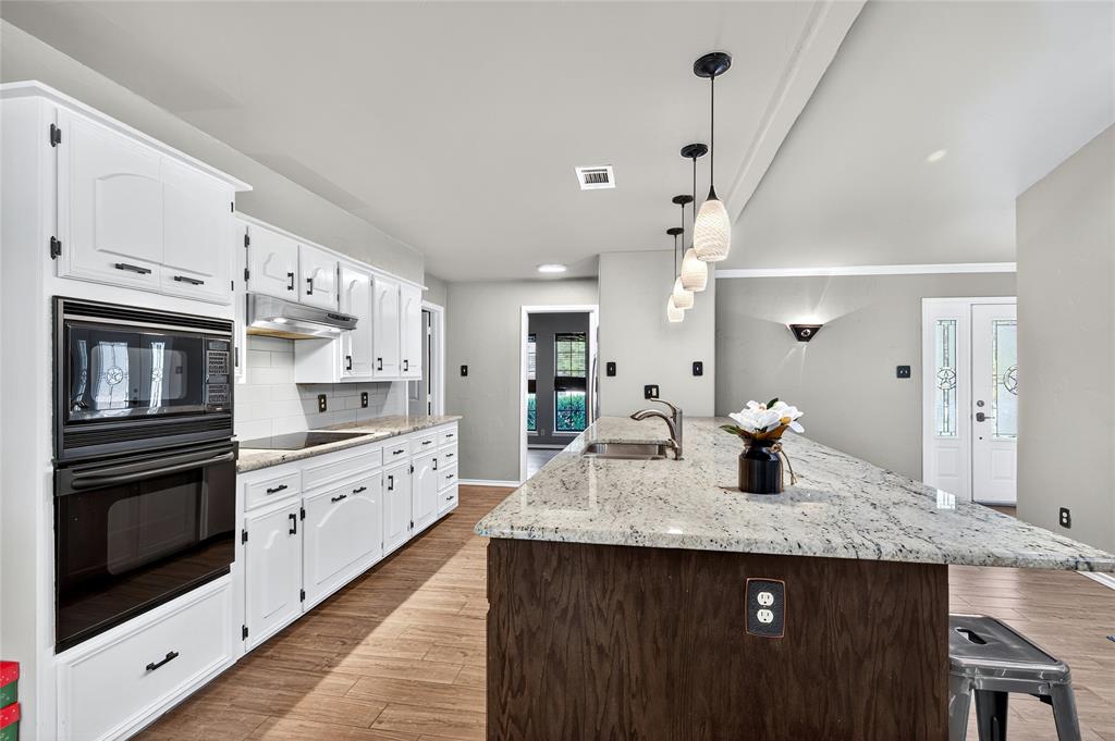 1610 Idlewood Drive Sherman, TX 75092 - Photo 11 of 31 a kitchen with granite countertop kitchen island a stove a sink dishwasher and white cabinets with wooden floor