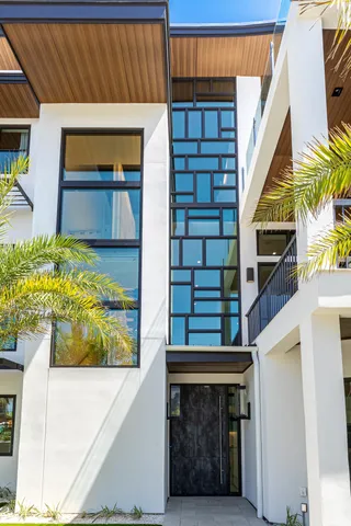 a view of a white house with a small yard and potted plants