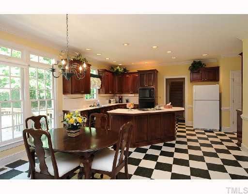7705 Lambroll Lane Raleigh, NC 27613 - Photo 2 of 12 a kitchen with a dining table and white appliances