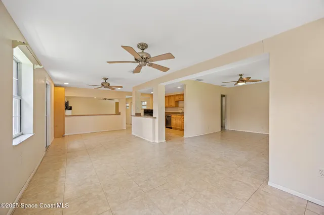 an empty room with a kitchen and a ceiling fan