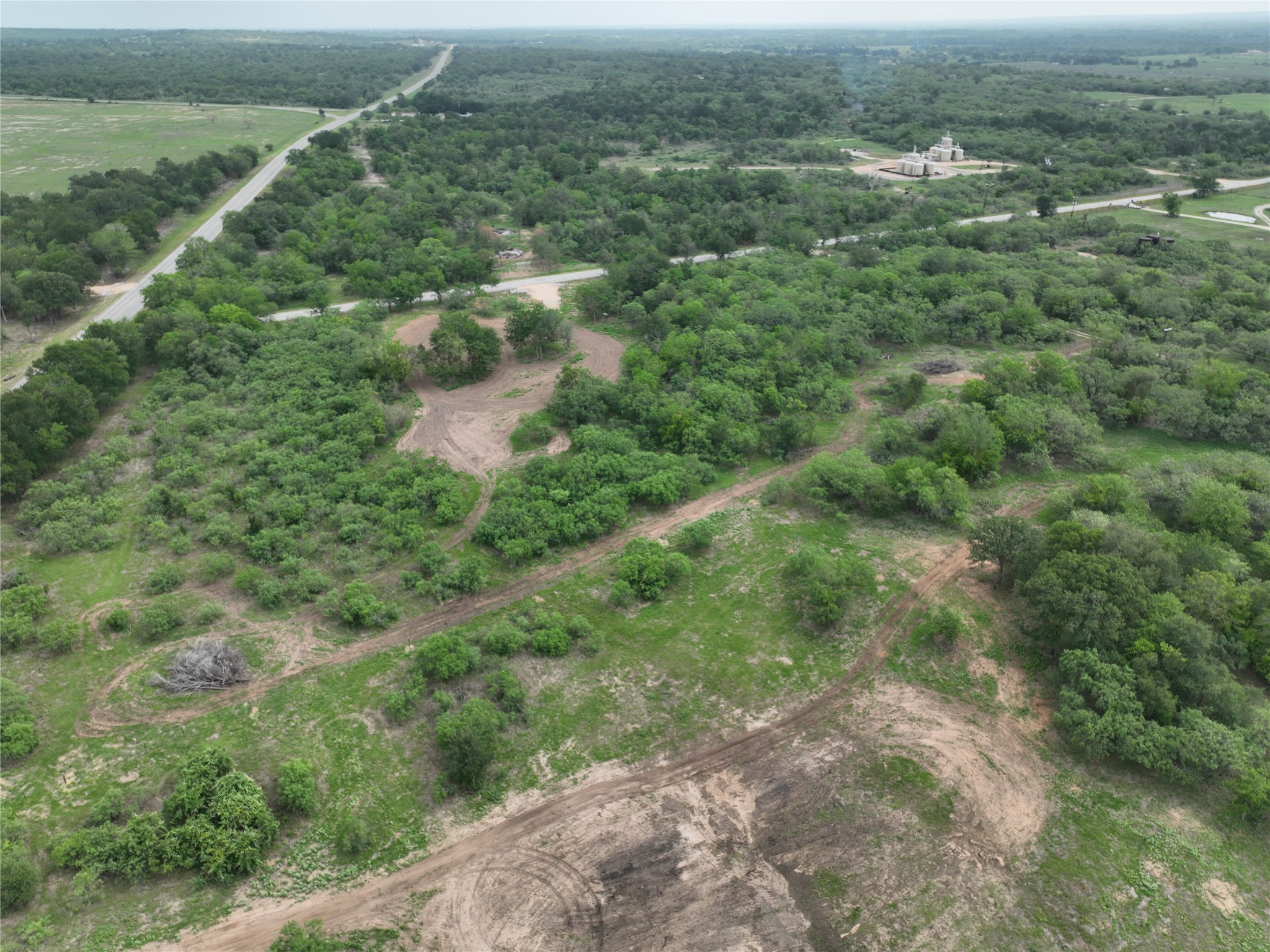 150 Pumper Road Luling, TX 78648 - Photo 8 of 24 Vast, verdant landscape unfolds with a distant road winding through dense foliage.