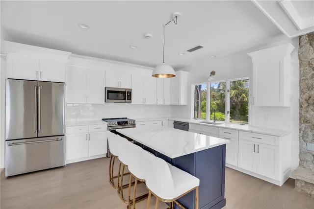 a kitchen with stainless steel appliances granite countertop a refrigerator a sink dishwasher a stove and a refrigerator with wooden floor