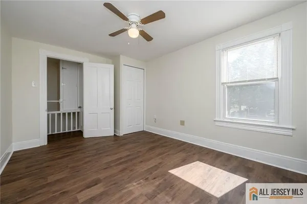 an empty room with wooden floor closet and windows