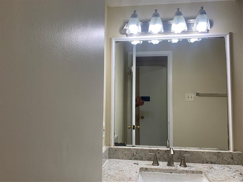 12482 Abrams Road, Unit 1303 Dallas, TX 75243 - Photo 23 of 30 Granite-finish countertop with an undermount sink, brushed nickel faucet, and a four-light vanity fixture