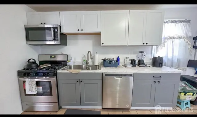 a kitchen with stainless steel appliances granite countertop a stove a sink and white cabinets