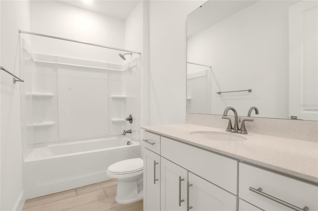 3723 Malad Way Tavares, FL 32778 - Photo 12 of 24 a bathroom with a granite countertop sink a toilet and bathtub