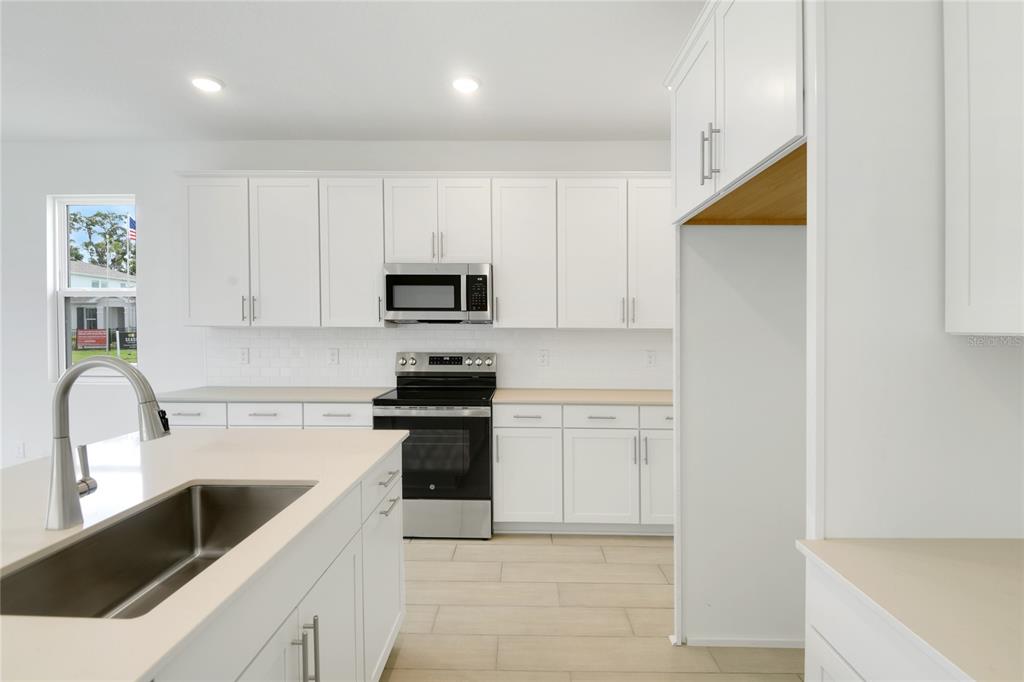 3723 Malad Way Tavares, FL 32778 - Photo 8 of 24 a kitchen with white cabinets and stainless steel appliances