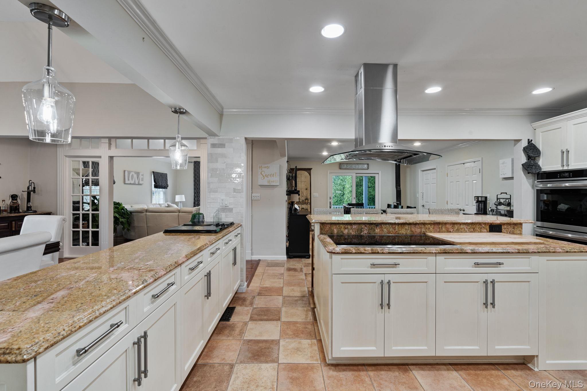 6 Daniel Way Setauket, NY 11733 - Photo 41 of 41 Kitchen with open floor plan, white cabinetry, light stone counters, decorative light fixtures, and crown molding