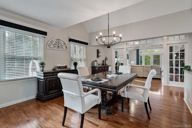 a dining room with wooden floor a chandelier a wooden table and chairs