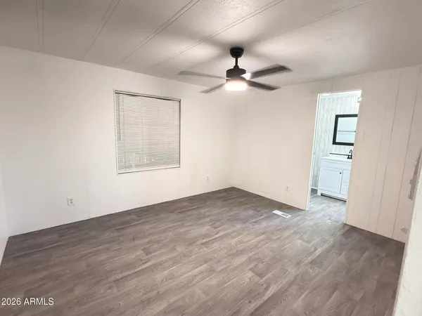 an empty room with wooden floor ceiling fan and windows