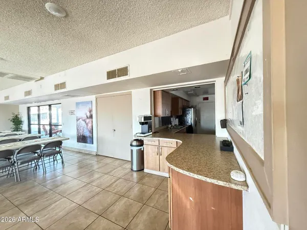 a large living room with stainless steel appliances kitchen island granite countertop a table chairs in it and a large window