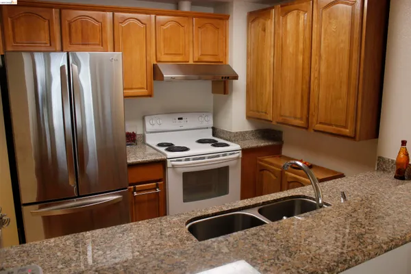 a kitchen with stainless steel appliances granite countertop a refrigerator a stove and a sink