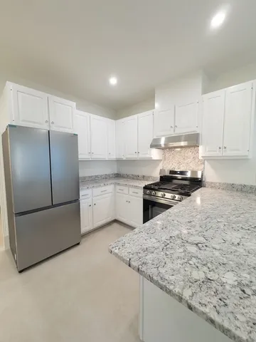 a kitchen with stainless steel appliances granite countertop a refrigerator sink and white cabinets