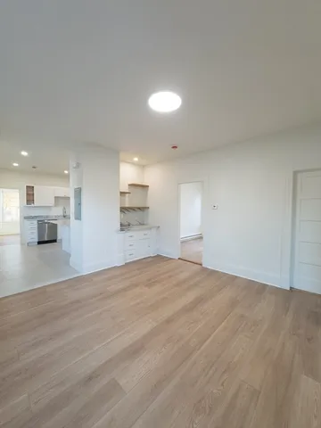 a view of empty room with kitchen and window