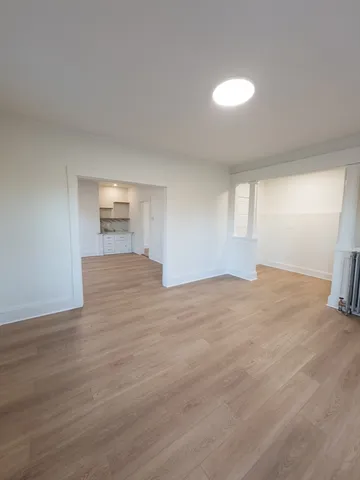 a view of an empty room with wooden floor and closet