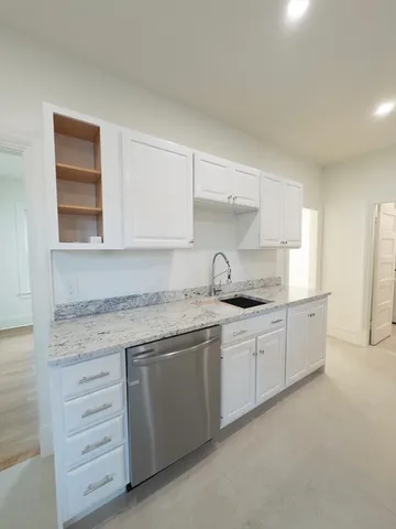 a kitchen with granite countertop white cabinets and sink