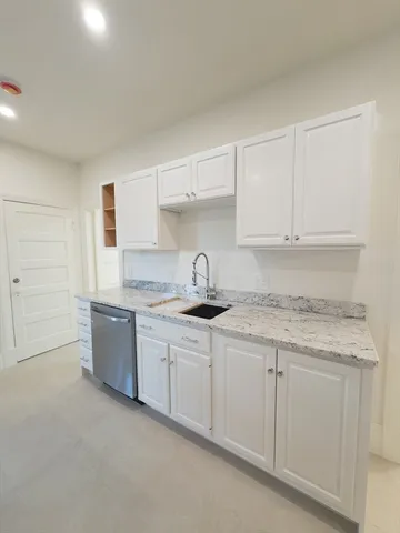a kitchen with granite countertop white cabinets and appliances