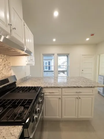 a large white kitchen with a sink window and cabinets