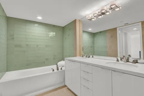 a bathroom with a double vanity sink mirror and bathtub