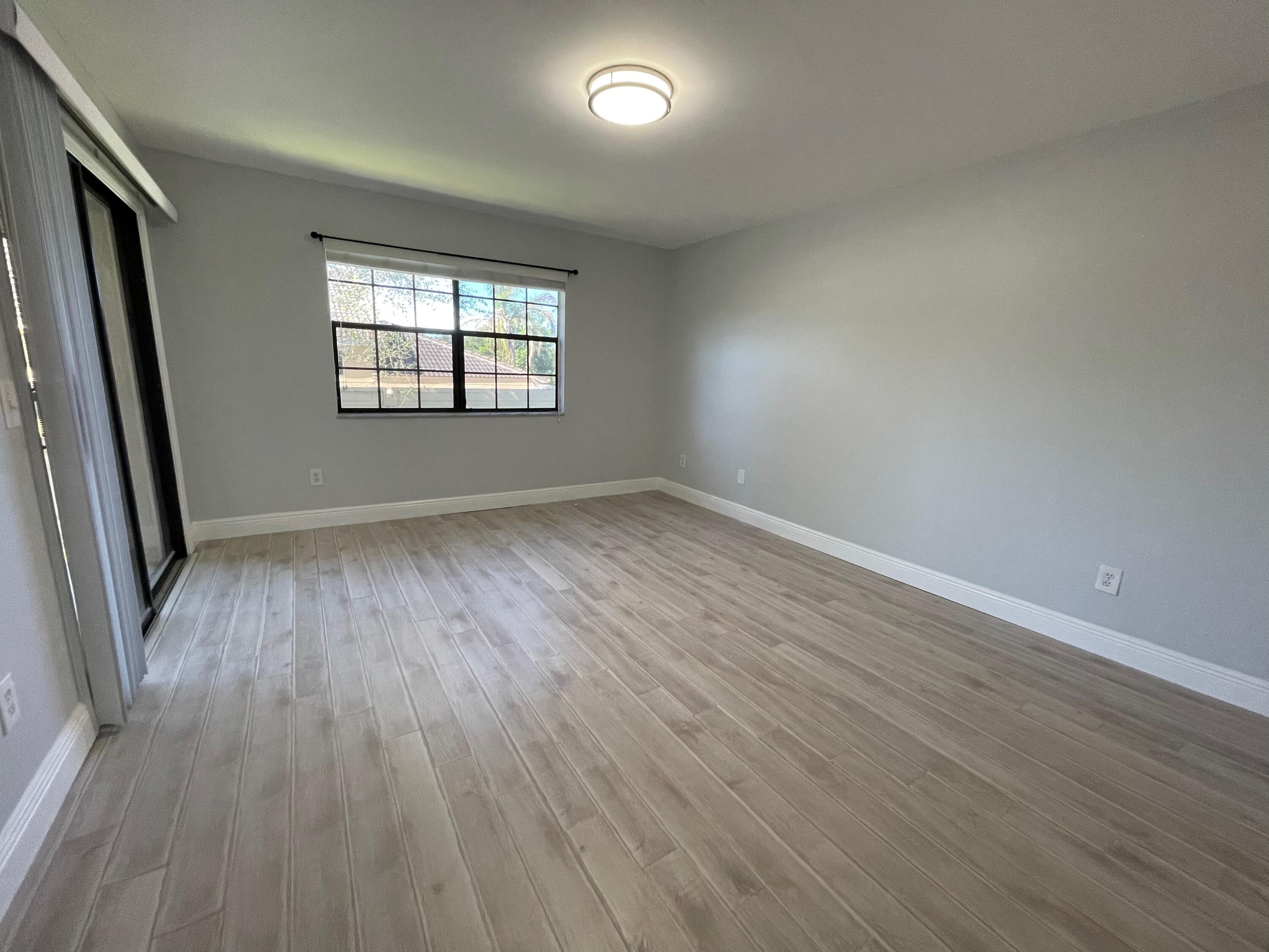 6691 Montego Bay Boulevard, Unit H Boca Raton, FL 33433 - Photo 18 of 22 an empty room with wooden floor and windows