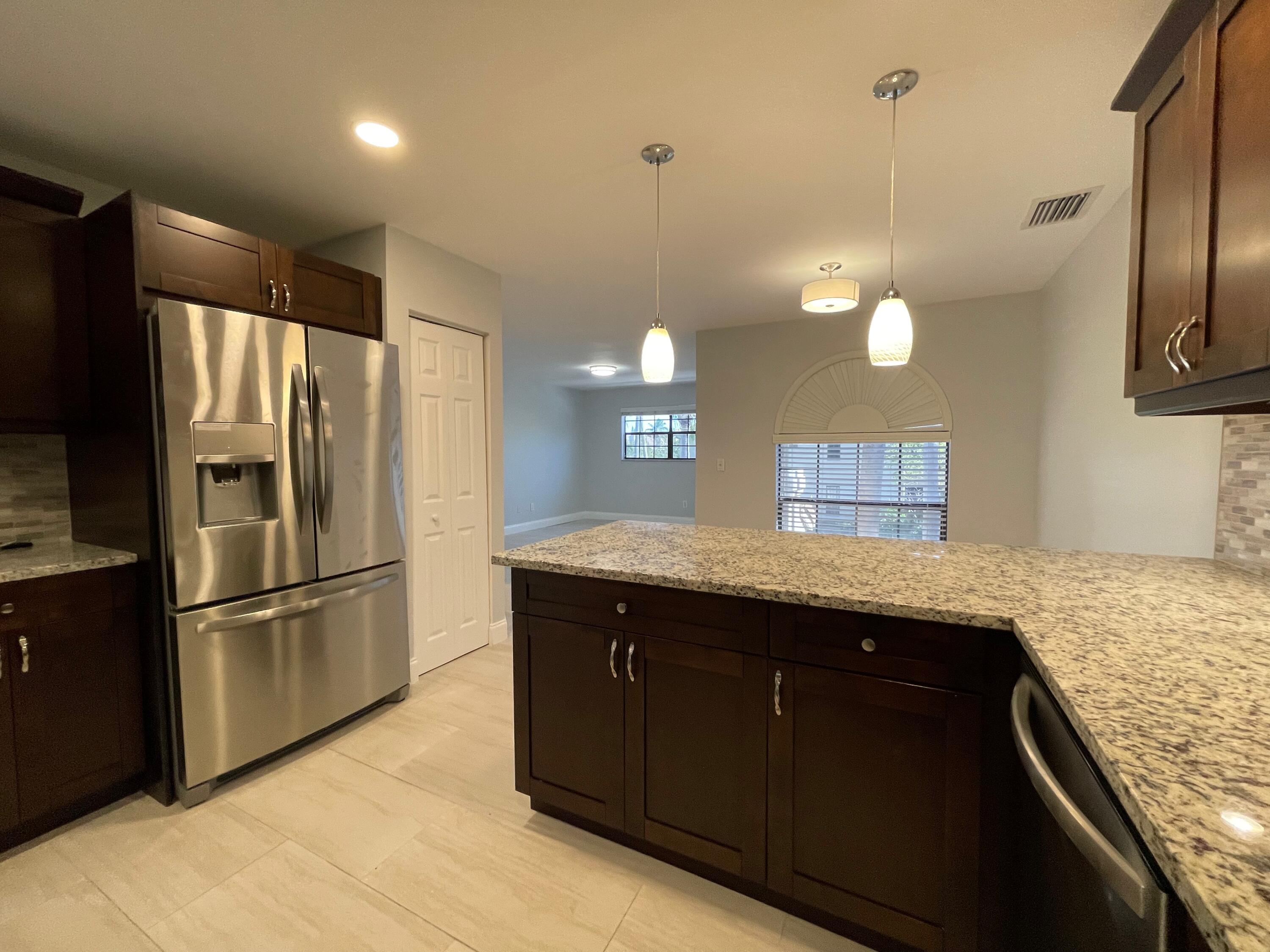 6691 Montego Bay Boulevard, Unit H Boca Raton, FL 33433 - Photo 6 of 22 a kitchen with stainless steel appliances granite countertop a refrigerator a sink and a stove