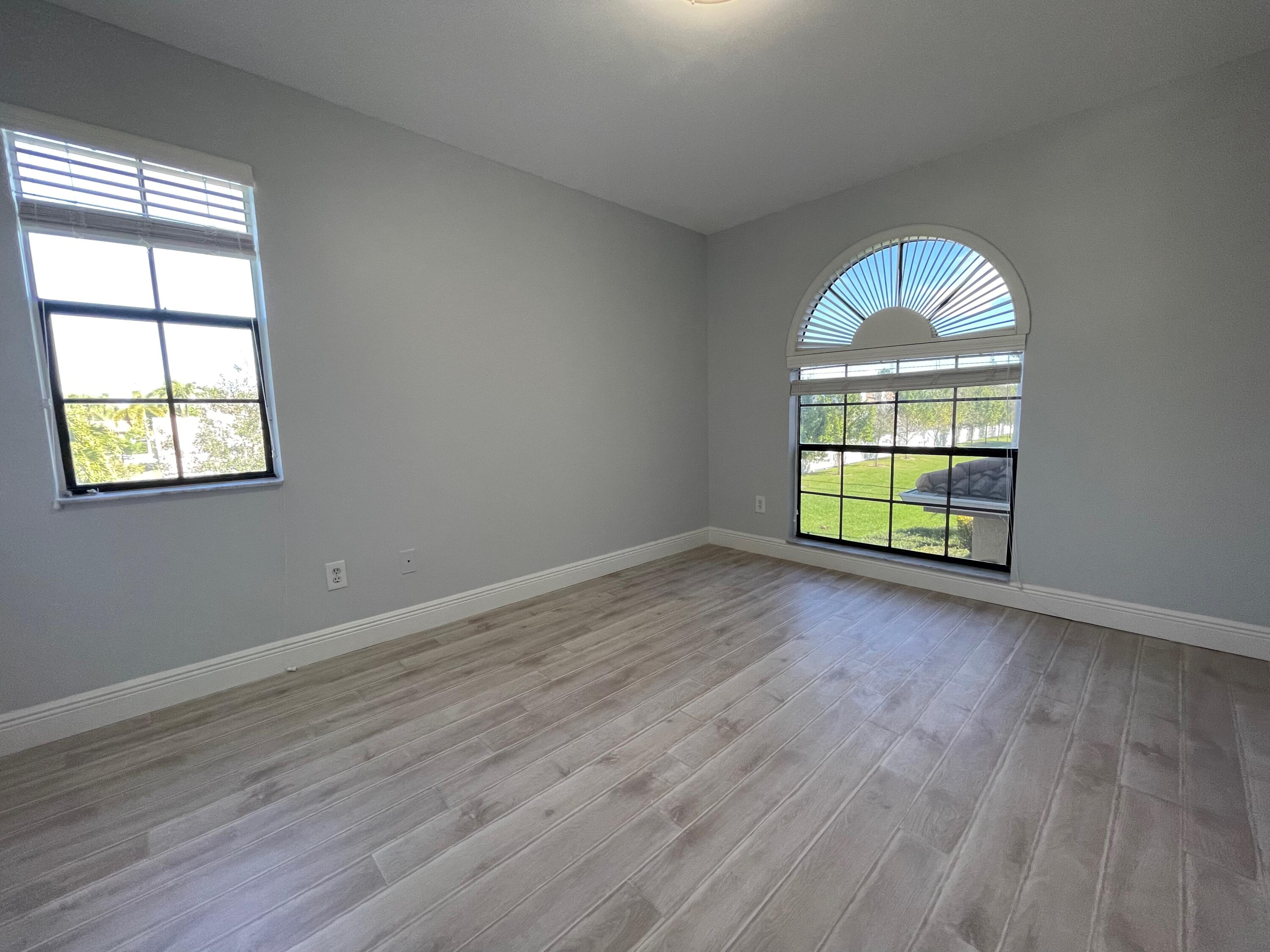 6691 Montego Bay Boulevard, Unit H Boca Raton, FL 33433 - Photo 9 of 22 an empty room with wooden floor and windows