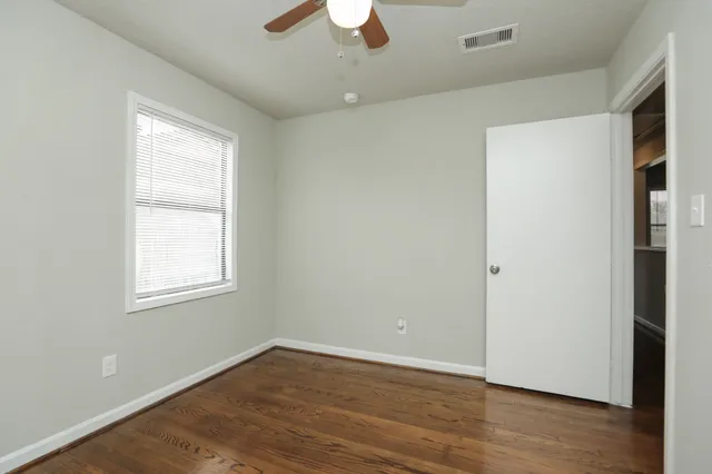 an empty room with wooden floor chandelier fan and window