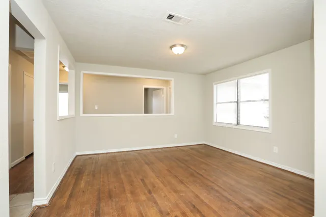 an empty room with wooden floor and windows