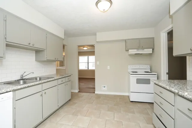 a kitchen with granite countertop white cabinets and white appliances