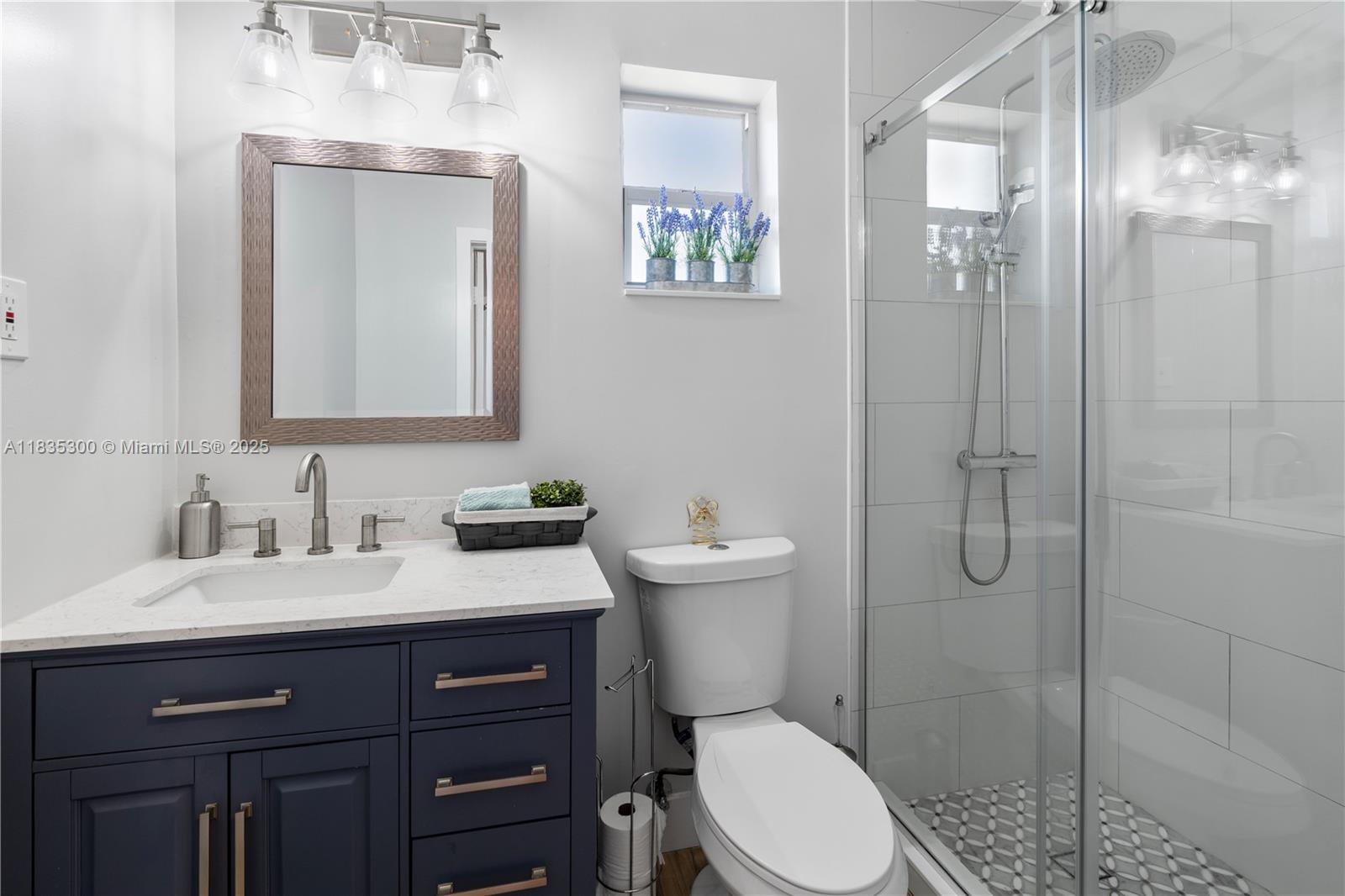 4025 Washington Street Hollywood, FL 33021 - Photo 10 of 24 a bathroom with a toilet a sink a glass door a shower a mirror and vanity