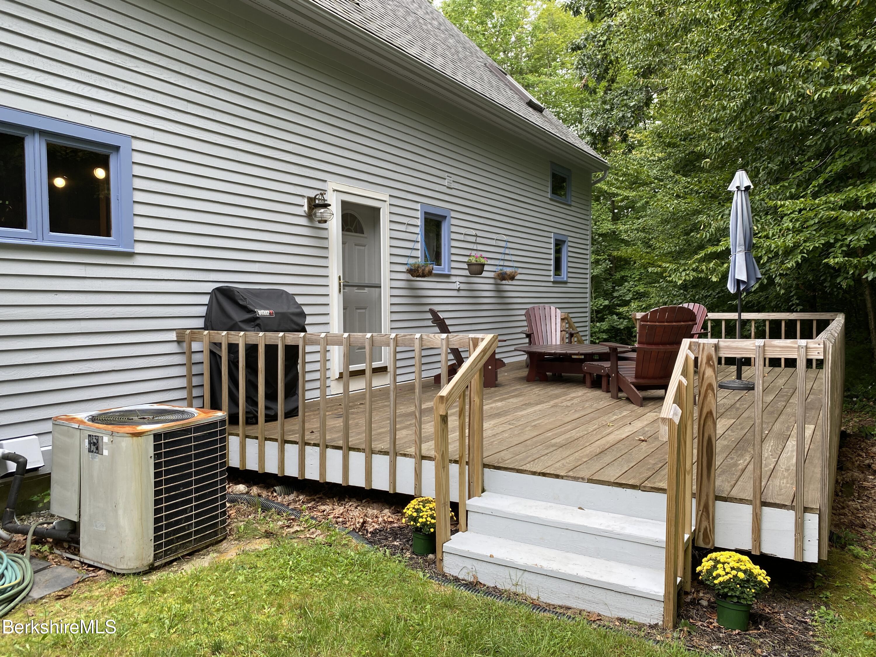 161 Capt Whitney Road Becket, MA 01223 - Photo 28 of 29 a view of a deck with two couches and a floor to ceiling window with wooden fence