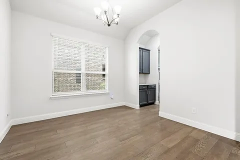 an empty room with wooden floor cabinet and windows