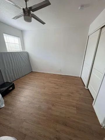 a view of an empty room with wooden floor and a window