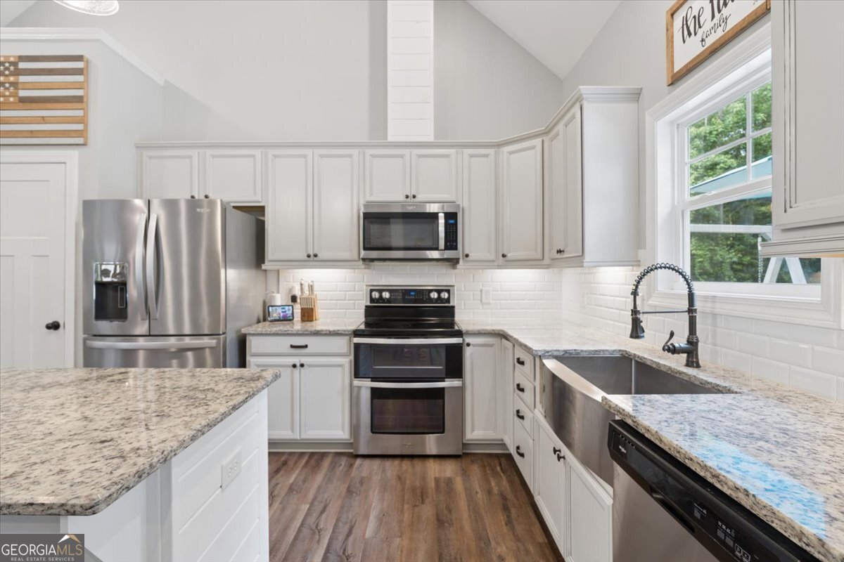 683 Teagle Road Forsyth, GA 31029 - Photo 15 of 50 a kitchen with stainless steel appliances granite countertop a stove top oven a sink dishwasher a refrigerator and a oven with wooden floor