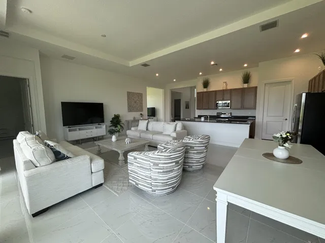 a living room with couches a flat screen tv and kitchen view