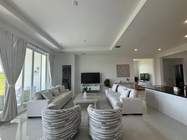 a living room with furniture a flat screen tv and large windows