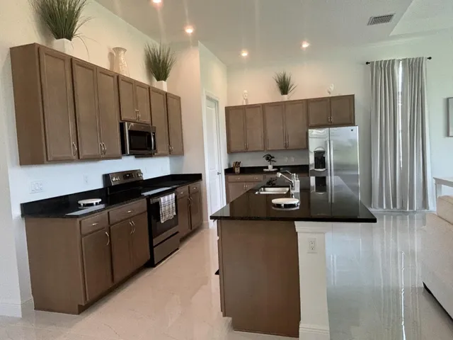 a kitchen with stainless steel appliances granite countertop a refrigerator a stove a sink and a microwave