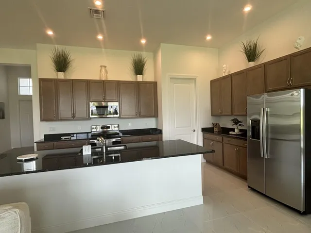 a kitchen with stainless steel appliances granite countertop a stove a refrigerator a sink a oven and a refrigerator with wooden floor