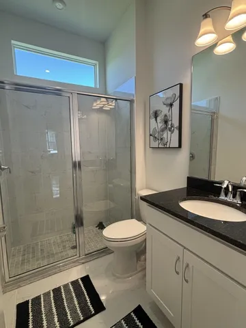 a bathroom with a granite countertop sink toilet a mirror and shower
