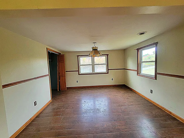 a view of an empty room with window and wooden floor