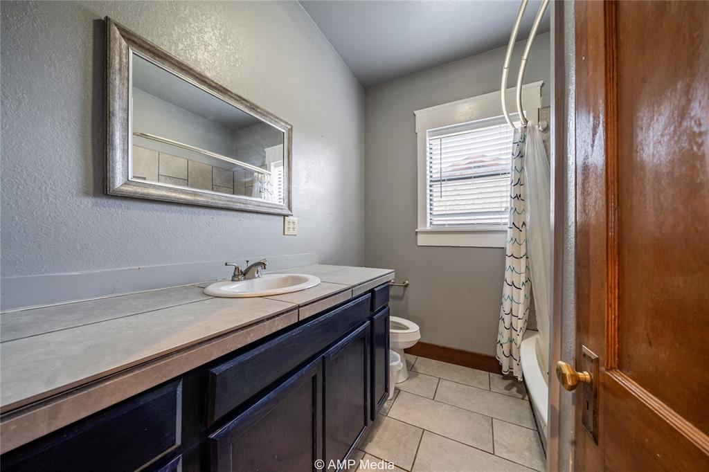 506 East Beauregard Street Rotan, TX 79546 - Photo 9 of 25 a bathroom with a granite countertop sink a mirror and a toilet
