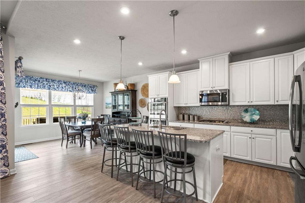 107 High Pointe Drive Washington, PA 15301 - Photo 12 of 38 a kitchen with stainless steel appliances granite countertop a stove top oven a sink a dining table and chairs with wooden floor