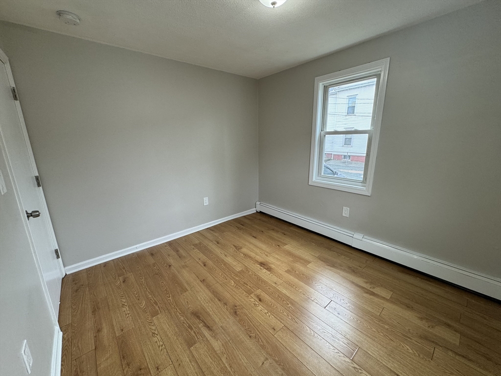138 Franklin Street, Unit 3 Lynn, MA 01902 - Photo 9 of 11 an empty room with wooden floor and windows